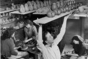 In einer Keramik-Werkstatt in Hamburg-Volksdorf. Arbeiterinnen drehen mittels einer Töpferscheibe Gefäße aus Ton. Die gebrannte Ware wird in ein Regal geschoben.