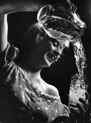 Das Modell Eva Roscher gießt Wasser aus einer Karaffe in ein Glas. Aufnahme für einen Prospekt der Hamburger Wasserwerke aus dem Jahr 1956