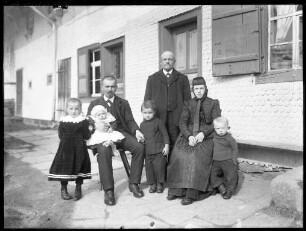 Familie vor einem Bauernhaus