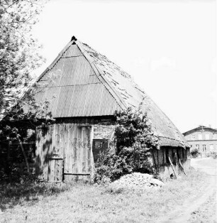 Fachwerkkate mit beschädigtem Dach: davor Schutthaufen: links Baum: hinten rechts Bauernhaus
