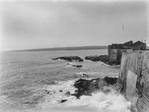 Am Meer : Blick von einer Mauer, vermutlich an einer Stadt, auf das Meer