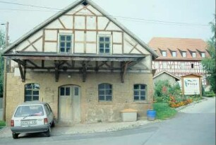 ehemalige Schmiede, Giebelansicht mit Vordach und gepflastertem Vorplatz