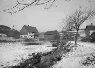 Paulsdorf, OT von Dippoldiswalde. Häusergruppe an der Einmündung des Paulsdorfer Dorfbaches von Südwesten. Links das im 30jährigen Krieg eingeäscherte und 1764 wieder aufgebaute Paulsdorfer Fachwerkaus an der Straße nach Seifersdorf, rechts die 1897 erbaute Bäckerei Wilhelm Wetzorke