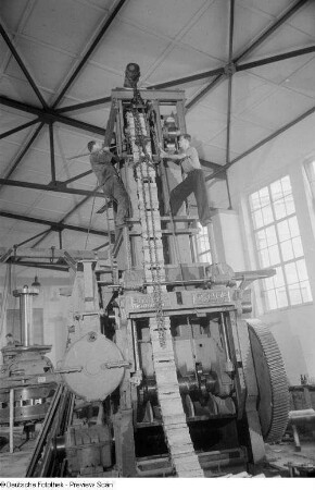 Zwei Arbeiter während des Aufbaus einer Maschine in einer Messehalle der Technischen Messe