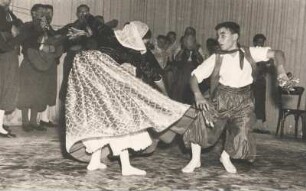 Folklore. Tänzer führen einen Volkstanz auf. Im Hintergrund die dazugehörige Musikgruppe
