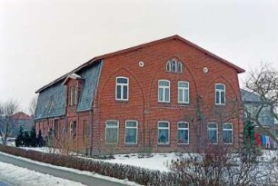 Up'n Knust (24): traufständiges Bauernhaus aus Backstein mit Mansarddach: Giebelseite Wohntrakt mit Lisenen und Spitzbögen, oben Jahreszahl 1870: Straßenfront, vorne Wohntrakt mit Zwerchgiebel über Eingangstür, hinten Wirtschaftstrakt: rechts hinten rückwärtiger Querbau: Gartenhecke