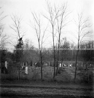 Aus einem fahrenden Zug fotografierter Friedhof mit kleinen Kreuzen