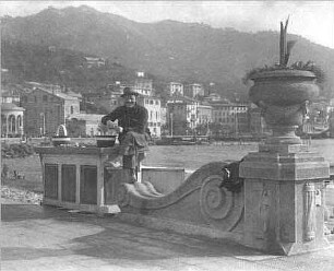 Mann, auf der Balustrade einer Uferpromenade sitzend (vielleicht an der Küste von Amalfi)