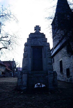 Kriegerdenkmal mit Kirchturm im Hintergrund