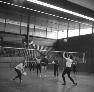 Volleyballtraining der Damen in einer Sporthalle. Werfen der Bälle über das Netz