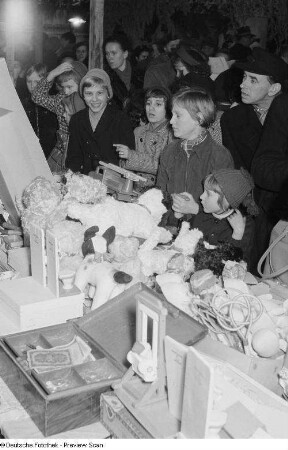 Verkaufsstand für Puppen und Spielwaren umringt von Besuchern auf dem Leipziger Weihnachtsmarkt bei Dunkelheit