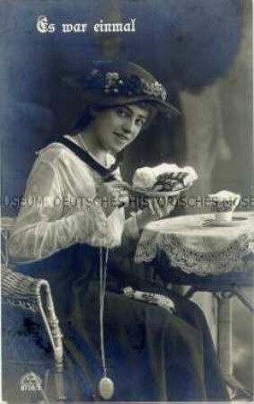 Postkarte mit kuchenessender junger Frau
