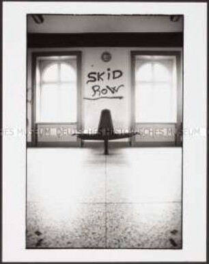 Leere Wartehalle mit Sitzbank in Seitenansicht und "Skid Row"-Schriftzug (Altersgruppe 18-21)