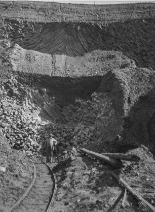 Basaltgrube : Ein Mann steht an Schienen vor einer Basaltgrube