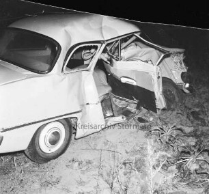 B 404: bei Tralau: Verkehrsunfall: auf Kreuzung mit Landstraße zwischen Tralau und Bad Oldesloe: Zusammenstoß von zwei Pkws: ein Unfallwagen auf Acker, mit eingedrückter Front, Beifahrertür geöffnet: im Dunkeln, 15. Oktober 1959