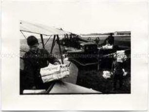 Sowjetsoldaten beladen ein Flugzeug mit Zeitungen auf dem Flugplatz Berlin-Tempelhof