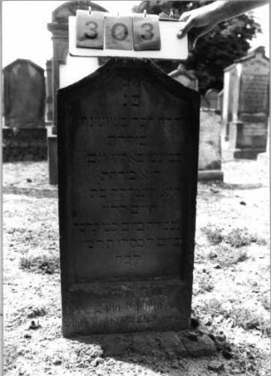 Grabstein 303 (Index: 99797853) Material: Sandstein, weiß Zustand: leicht verwittert Maße HxBxT: 87x45x10 cm Beschreibung: Stele, giebelartiger oben abgeflachter Abschluß, Sockel: Grabstein 303