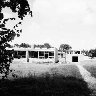 Grundschule Glashütte: Erweiterungsbau mit Klassenräumen, dahinter verglaster Rohbau der Turnhalle