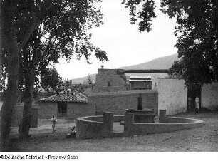 Platz mit Brunnenanlage (wohl in einem Dorf)