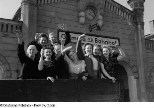 Winkende Erntehelfer vom VEB Mihoma auf einem Anhänger vor dem Bahnhofsgebäude