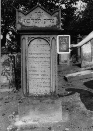 Grabstein 257 (Index: 100088137) Material: Sandstein Zustand: leicht verwittert Maße HxBxT: 160x58x33 cm Beschreibung: Stele auf Sockel mit Dreiecksgiebeldach, Inschriftennische mit Rundbogen Symbolik: kleiner Ornamentenschmuck am Rundbogen der Inschriftennische: Grabstein 257