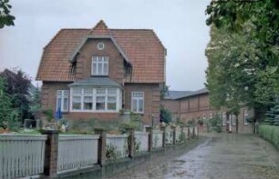 Schlamersdorf: Dorfstraße 21: Backsteinhaus: Seitenfront mit Standerker und Zwerchhaus: vorne links Garten, Gartenmauer mit Holzzaun: hinten rechts traufständiges Bauernhaus