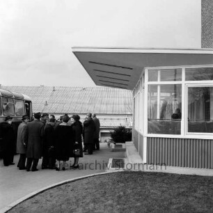 Kreistag in Reinfeld: Sitzung am 13. Februar 1962: Besichtigung der "Opal-Werke", Strumpffabrik Margaritoff & Schaffer GmbH: Kreistagsabgeordnete vor dem Eingang zum Werksgebäude: links Reisebus: hinten weiteres Werksgebäude