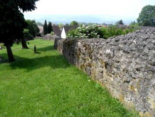 Kirchhof im Westen mit Kirchhofmauer (Wehrgang mit Steinbrüstung und Schießscharten abgetragen) in übersichtlichem Verlauf nach Süden