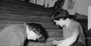 Zwei junge Frauen auf einer Treppe während der Vorbereitung einer Fotoausstellung