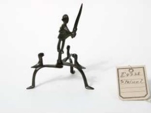 Männliche Figur auf Dreifuß