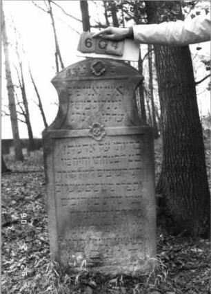 Grabstein 604 (Index: 100115270) Material: Sandstein Zustand: verwittert Maße HxBxT: 129x61x12 cm Beschreibung: Stele mit konkav eingezogenem Segmentbogenabschluß, eingetieftes, zweigeteiltes Schriftfeld Symbolik: Blüten Besonderheit: kulturhistorisch wertvoll / hist.-wiss. Gründe (Gemeindestellung): Grabstein 604