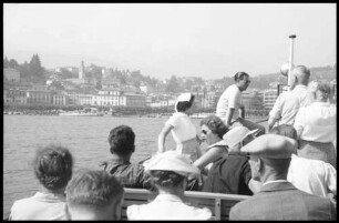 Lugano: Stadt vom See mit Motorbootgästen im Vordergrund