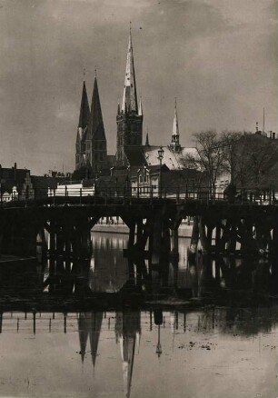 Lübeck. Blick vom Malerwinkel über die Trave zur Dankwartsbrücke, einer hölzernen Fußgängerbrücke. Im Hintergrund die Doppeltürme der Marien- und der Turm der Petrikirche