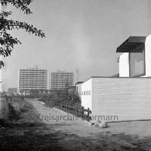 Im Hölk: vorne Wohngebäude, dahinter weitere Wohngebäude, im Hintergrund zwei Wohnhochhäuser: Blick nach Osten