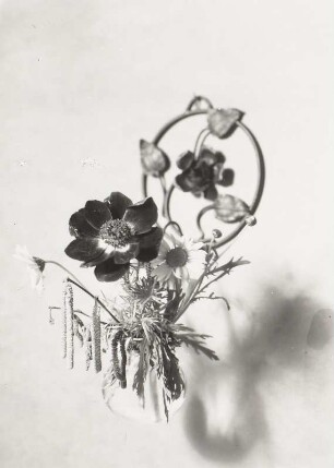 Stilleben. Blumenstrauß in einer Glasvase vor schmiedeeisernem Blütenring