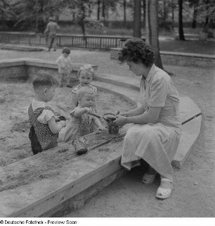 Mutter mit Kindern im Sandkasten auf einem Spielplatz im im Clara-Zetkin-Park
