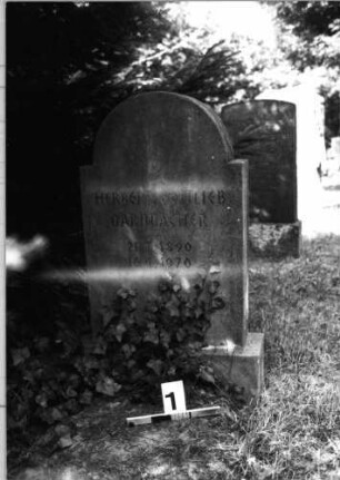 Grabstein 1 (Index: 100085318) Zustand: quer gebroch. /zusammengefügt m. Textverl. Maße HxBxT: 115x50x15 cm Beschreibung: Stele, Sockel, Segmentbogenabschluß: Grabstein 1