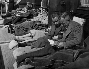 Auf dem Passagierschiff "Hansestadt Danzig" des Seedienstes Ostpreußen. Passagiere sitzen in Liegestühlen an Deck. Zwei Männer befinden sich in einem Gespräch