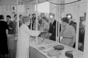 Besucher der Leipziger Herbstmesse 1955 an einem Kiosk mit Kuchen, im Vordergrund drei Verkäuferinnen