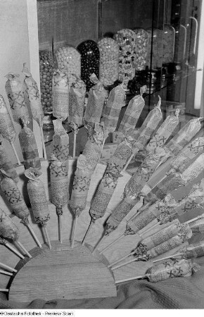 Süßwaren auf der Leipziger Herbstmesse 1954, im Vordergrund Süßigkeiten am Stiel, im Hintergrund Dragées und Bonbons in Gläsern