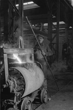 Radebeul. Eisengießerei, Handformgießen. Gießer beim Abstich am Schmelzofen, Schmelze wird in eine schienenverfahrbare Krangießpfanne geleitet