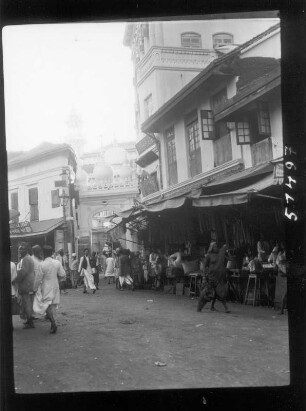 Bombay. Belebte Geschäftsstraße mit Passanten gegen eine Moschee