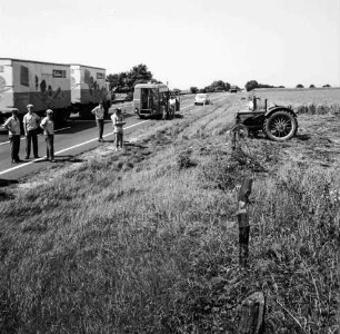 Mord an Brigitte Wetzenstein-Ollenschläger: Bundesautobahn A 1 bei Reinfeld: Leichenfundort im Graben neben Seitenstreifen am 19. August 1972: rechts Trecker nach Mähen eines Teils des Grases und des angrenzenden Getreidefeldes: links Polizisten sowie Landwirt am Straßenrand: dahinter fahrender Lkw, Polizeifahrzeug sowie Pkw: hinten rechts weitere Fahrzeuge und Bäume