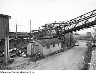 Löbau. Kohletransportbahn (Industrieseilbahn) zwischen Bahnhof und ehemaliger Färberei Römer AG. Stahlkonstruktion der Seilbahn, über eine Straße führend. Blick über ein Gebäude gegen Plattform