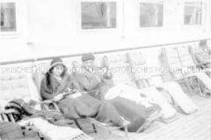 Passagiere in Liegestühlen an Deck des Hochseepassagierdampfers "Bremen", lesend, mit Wolldecke über den Knien