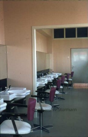 Kreisberufsschule [Ahrensburg]: Hermann-Löns-Straße: Innenaufnahme: Unterrichtsraum für Friseure: Haarwaschbecken, Stühle