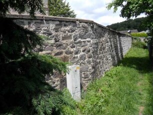Nonnenroth-Evangelische Kirche - Kirchhofmauer im Nordosten über Nordflanke (Wehrgang mit Schießscharten abgetragen) von Feldseite mit Werksteinen im Mauersteinverband