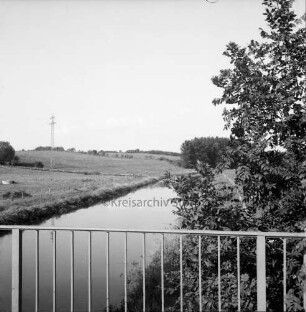 TTrave: Blick von der Brücke auf Travetal mit angrenzender Knicklandschaft: rechts Büsche: hinten links Strommast der Überlandleitung auf Weide