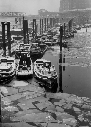 Hamburg. Die in der Altstadt gelegenen Kaianlagen am Binnenhafen, genannt Kajen, im Winter. Sie befinden sich zwischen Nikolai- und Alsterfleet. Im, mit Eisschollen bedeckten Hafenbecken liegen kleine Fähren vor Anker