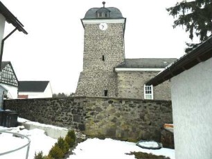 Ansicht von Süden mit Kirche (Kirchturm im Kern Romanisch-Mittelgeschoß mit Schlitzscharten-einstige Wehrplattform 1792 ersetzt) über Kirchhofmauer (Wehrgang im 18 Jh abgetragen)